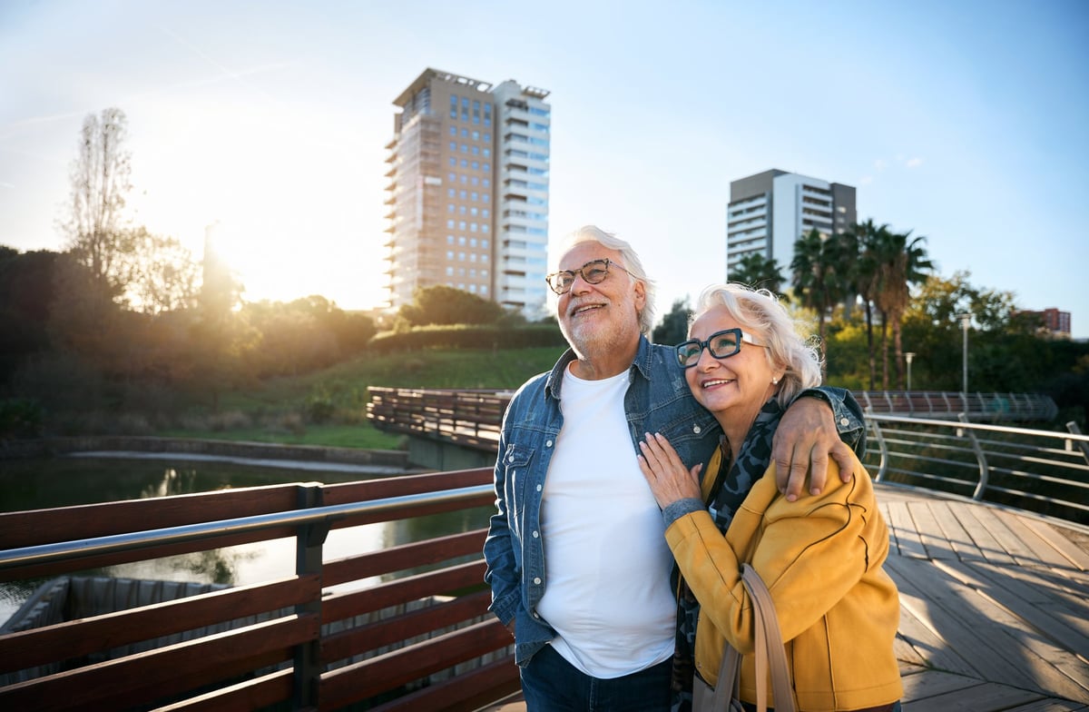 Senior couple walking arm in arm, smiling at sunset